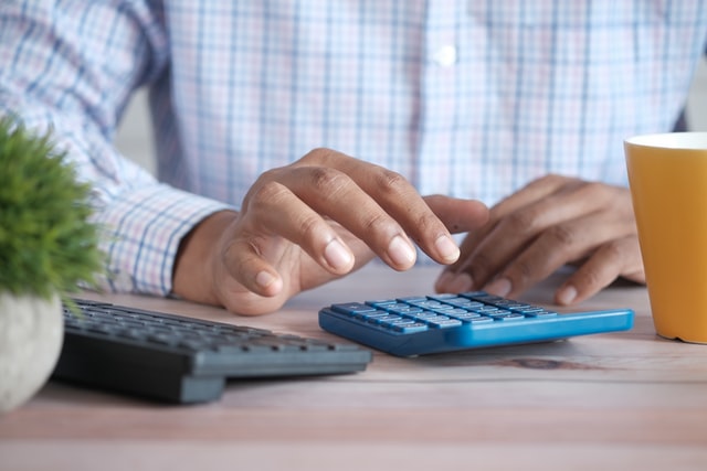 person putting numbers into a blue calculator